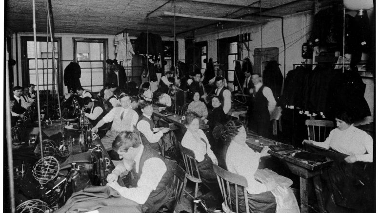 Black and white photograph of long rows of workers in an early shop scene.