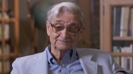 Portrait of E.O Wilson wearing a suit and smiling.