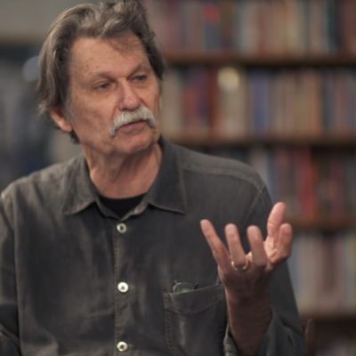 Portrait of Gregory Orr in mid-speech with hands gesturing.