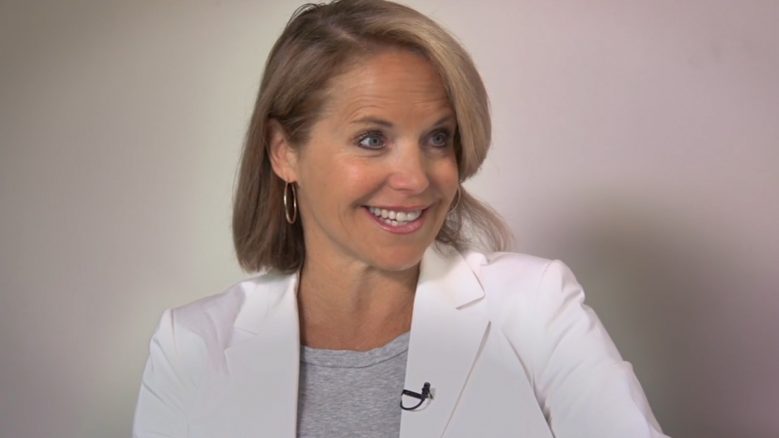 Portrait of Katie Couric wearing a white blazer and smiling.