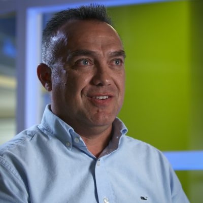 Edgardo Ochoa wearing a blue collared button-up shirt and smiling.