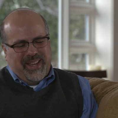 Portrait of Rafael Campo smiling and looking downward