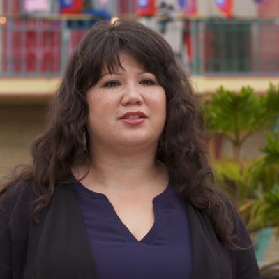 Portrait of Marina Perez Wong wearing a black top and in mid-speech.