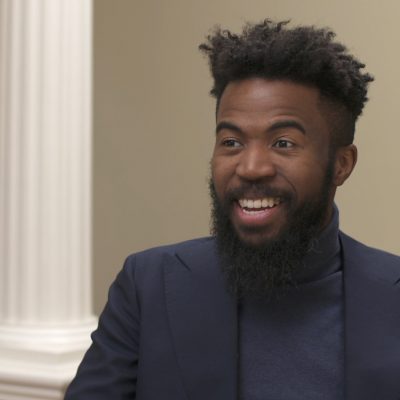 Portrait of Joshua Bennett wearing a suit and smiling.