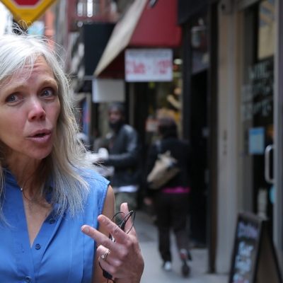 Author Karen Karbiener wearing a blue top, in the middle of speaking and gesturing with hands.