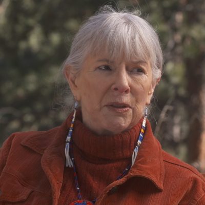 Portrait of Linda Hogan wearing a red sweater, in the middle of speaking.