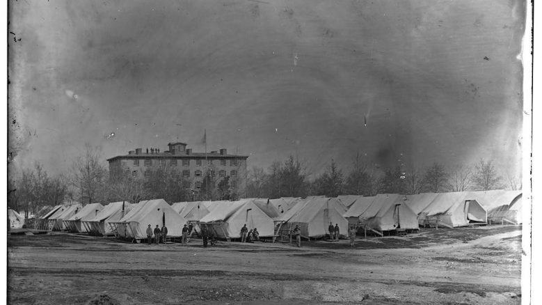 Black and white photograph depicting rows of white tents