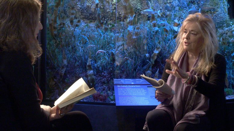 Jorie Graham seated, facing Elisa New, holding a book and speaking.