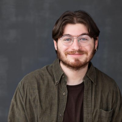 Headshot of Gideon Leek, wearing a brown shirt and smiling