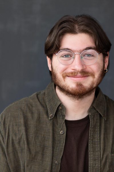 Headshot of Gideon Leek, wearing a brown shirt and smiling
