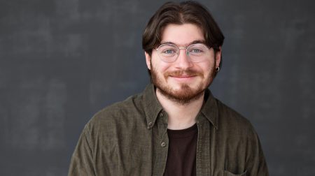 Headshot of Gideon Leek, wearing a brown shirt and smiling