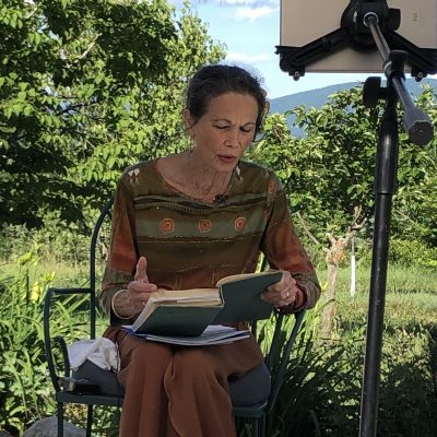 Julia Alvarez sits and reads from a book.