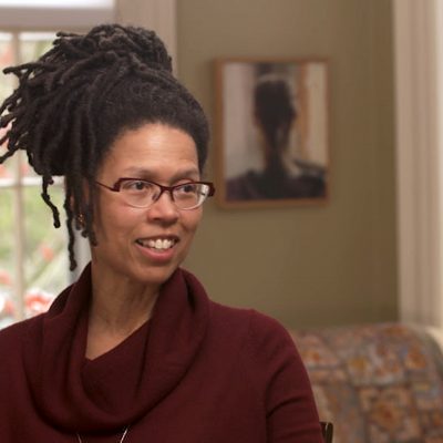 Evie Shockley wears a red top while in the middle of talking and gesturing with her hand