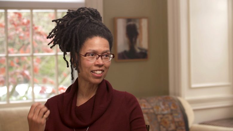 Evie Shockley wears a red top while in the middle of talking and gesturing with her hand