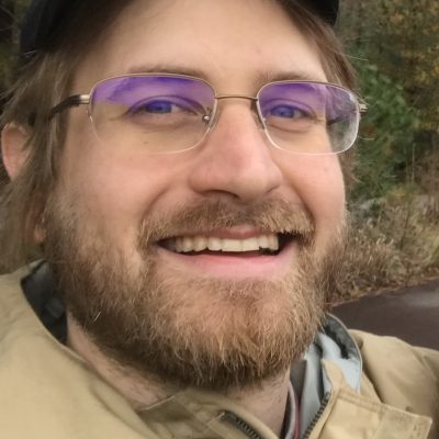 Portrait of Ross Weissman wearing a hat and smiling.