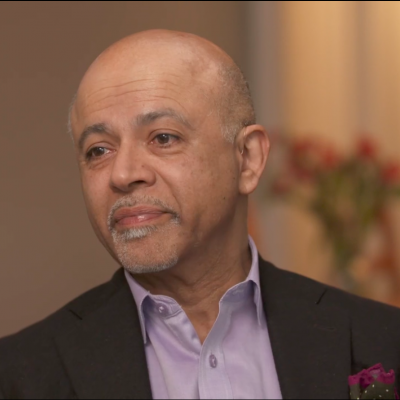 Portrait of Abraham Verghese wearing a suit and looking off to the left.