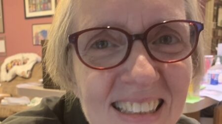 Cathy Nicastro smiles while wearing red glasses