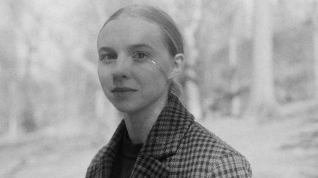 Black and white portrait of Elinor Hitt wearing plaid coat and smiling.