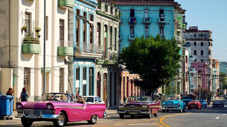 Colorful buildings and retro cars line a street in Havana, Cuba.