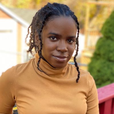 Portrait of Geraldine Joseph wearing a yellow turtleneck and smiling.