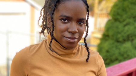 Portrait of Geraldine Joseph wearing a yellow turtleneck and smiling.