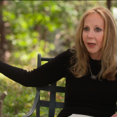 Rebecca Goldstein, wearing a black long-sleeve, in the middle of speaking while gesturing with her right hand.