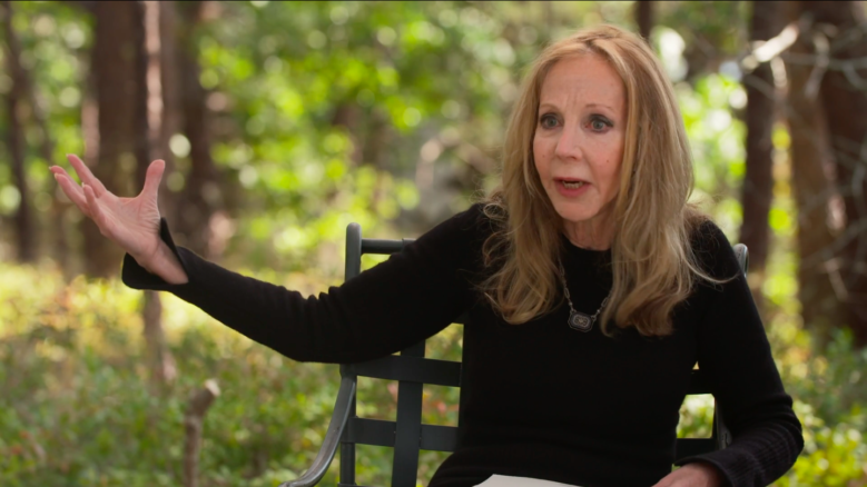 Rebecca Goldstein, wearing a black long-sleeve, in the middle of speaking while gesturing with her right hand.