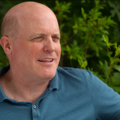 Daniel Schrag, wearing a blue collared shirt, in the middle of speaking while looking to the right