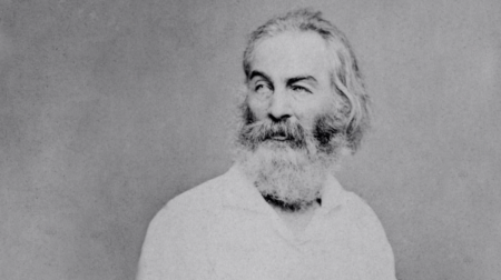 Black and white portrait of American poet Walt Whitman wearing a white collared shirt and gazing to the left.