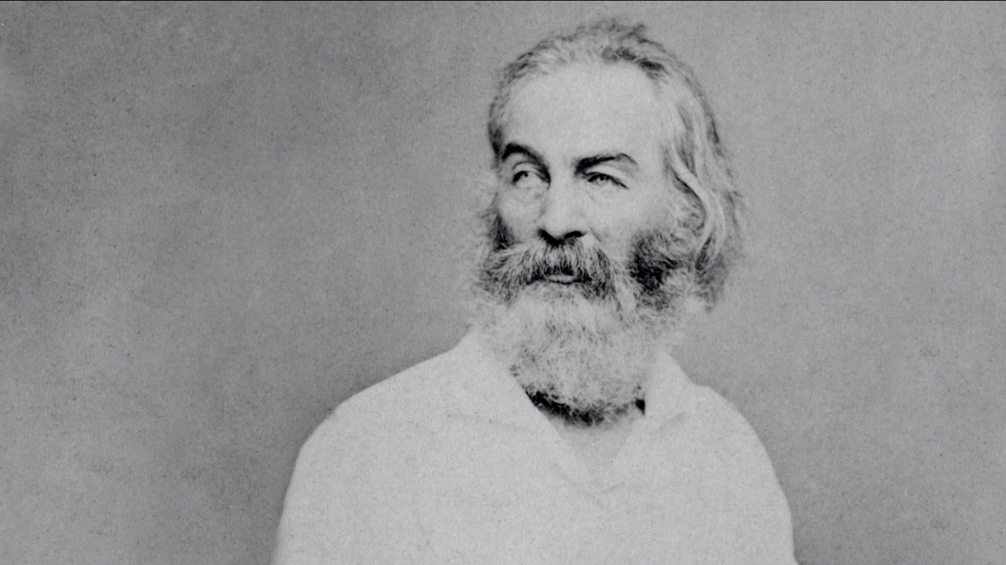 Black and white portrait of American poet Walt Whitman wearing a white collared shirt and gazing to the left.
