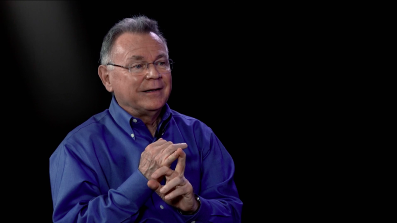 Alberto Ríos, wearing a blue button-up, gesturing while in the middle of speaking