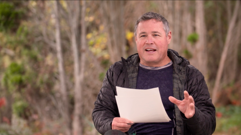 Wildlife biologist and conservationist Jeff Corwin gesturing and holding paper while in the middle of speaking
