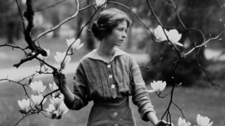Black and white portrait of Edna St. Vincent Millay holding flowering tree branches and looking to the side