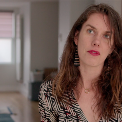 Author Leslie Jamison, wearing a black and white top looks up in thought