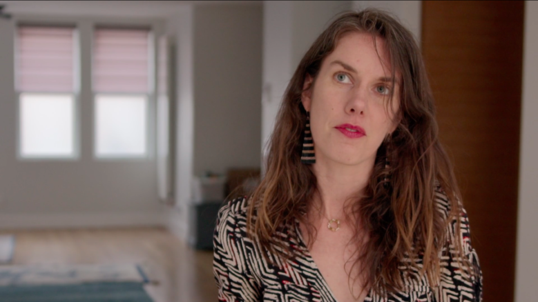 Author Leslie Jamison, wearing a black and white top looks up in thought