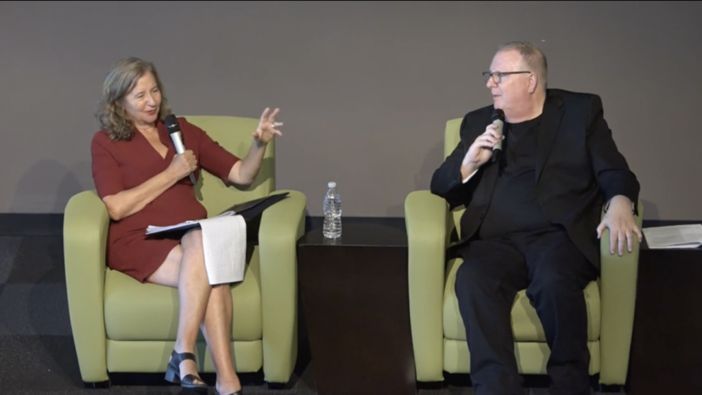 Elisa New, in a red dress, and Jeffrey Kennedy, in a black suit, sit as they discuss poetry at the Welcome to the West event.