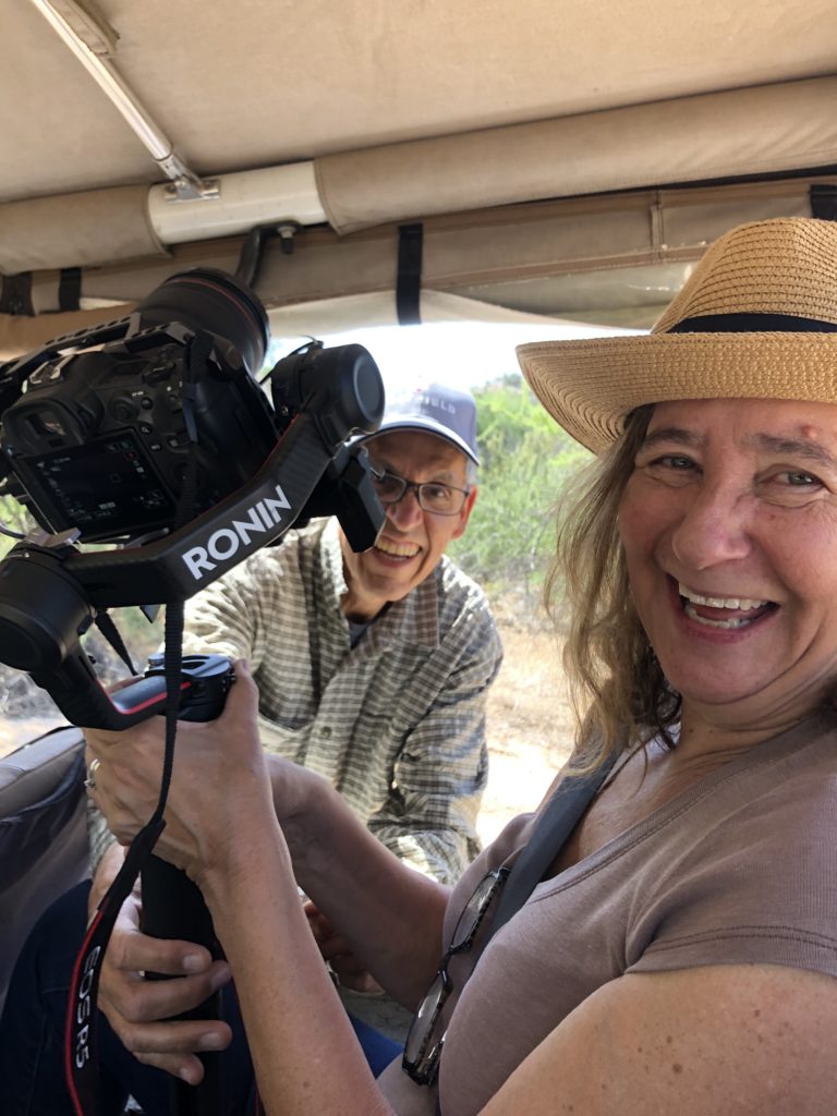 Host Elisa New holds a camera with crew member Gerard Watson in the background.