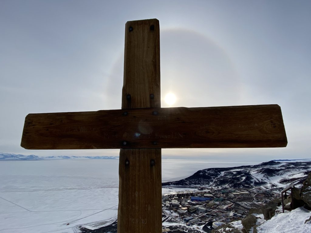 A close up of the wooden cross, with an icy landscape behind it.