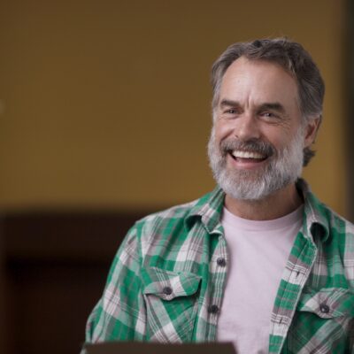 Murray Bartlett, wearing a green flannel, smiles.