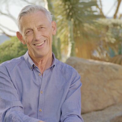 Sir Jonathan Bate, wearing a blue button-up, smiles