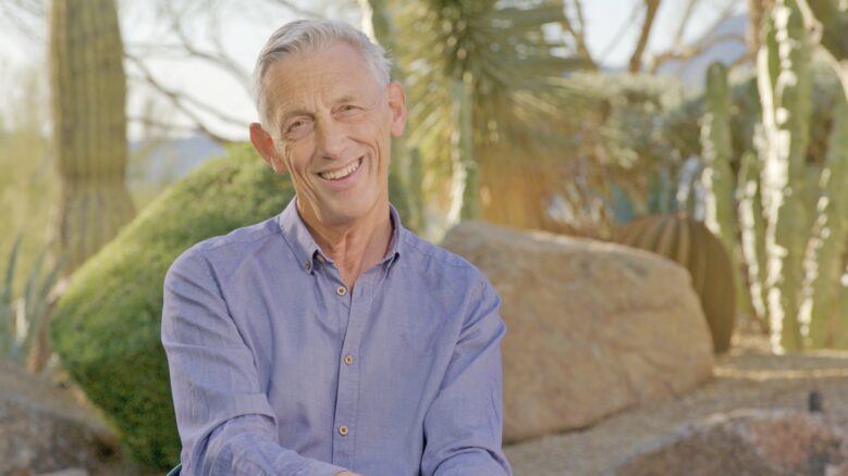 Sir Jonathan Bate, wearing a blue button-up, smiles