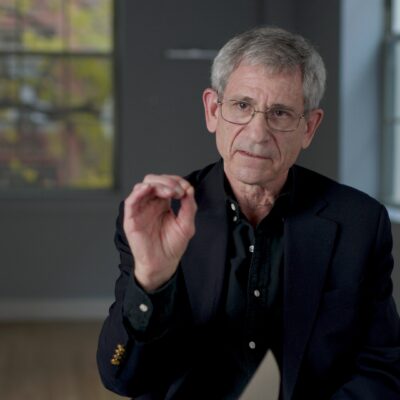 Jonathan Brent, wearing a black suit, gestures with his hand as he speaks.