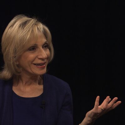 Andrea Mitchell, wearing a black top, gestures with her hand as she speaks.