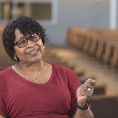 Dr. Patricia Neff, wearing a red top, gestures with her hand as she speaks.