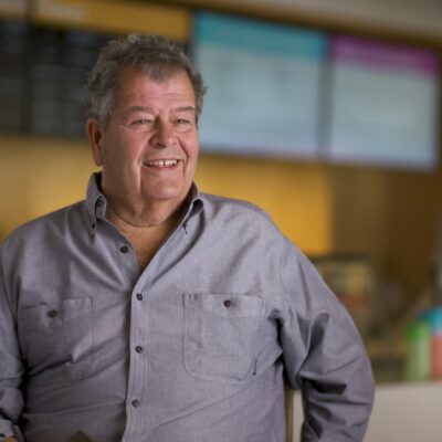 Gus Rancatore, wearing a button-up shirt, smiles