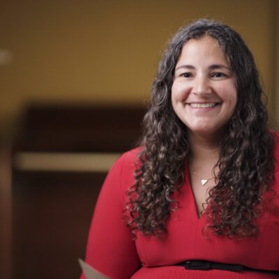 Laurie Santos, wearing a red top, smiles.