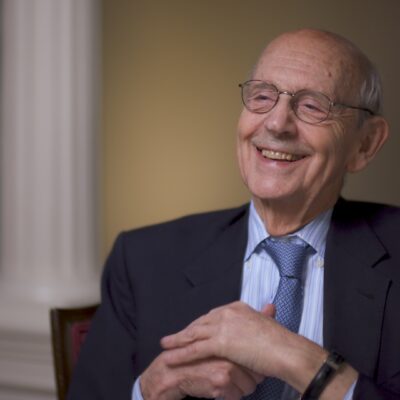 Stephen Breyer smiles while wearing a suit