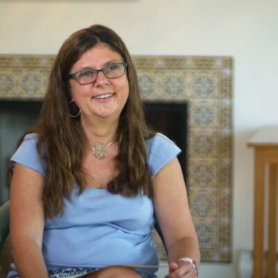 Betsey Stevenson wears a blue shirt and smiles while sitting in a chair