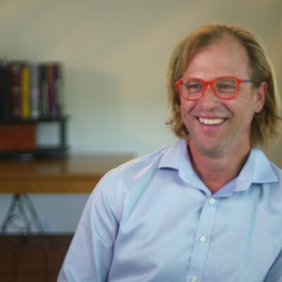 Justin Wolfers smiles while wearing a blue button-up shirt